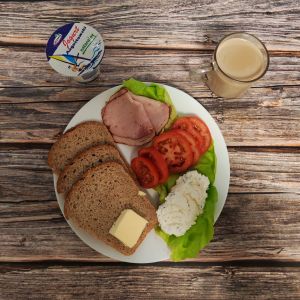 Zdjęcie przedstawia Dietę z ograniczeniem łatwoprzyswajalnych węglowodan&oacute;w: Masło extra Szynka pieczona w ogniu wieprzowa Sałata zielona Kawa zbożowa z mlekiem Chleb Graham Jogurt naturalny Twarożek z koperkiem Pomidor